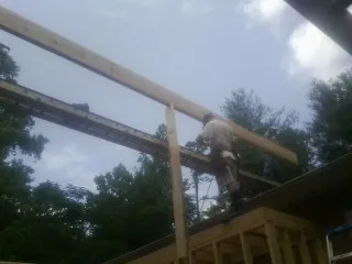 Carpenter setting a ridge beam over a new addition frame — Ice Dam Removal by Roofing Brothers in Oak City