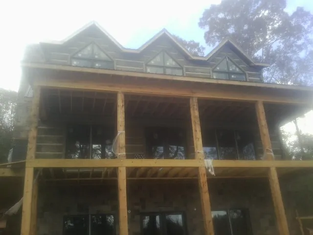 Dormers and porch framing on a large log home under construction — Roof Coating work by our crew in Oak City