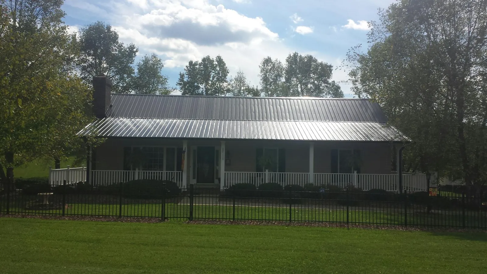 Gray metal roof on a brick ranch with a full width front porch — Gutter Guard Installation work by our crew in Oak City