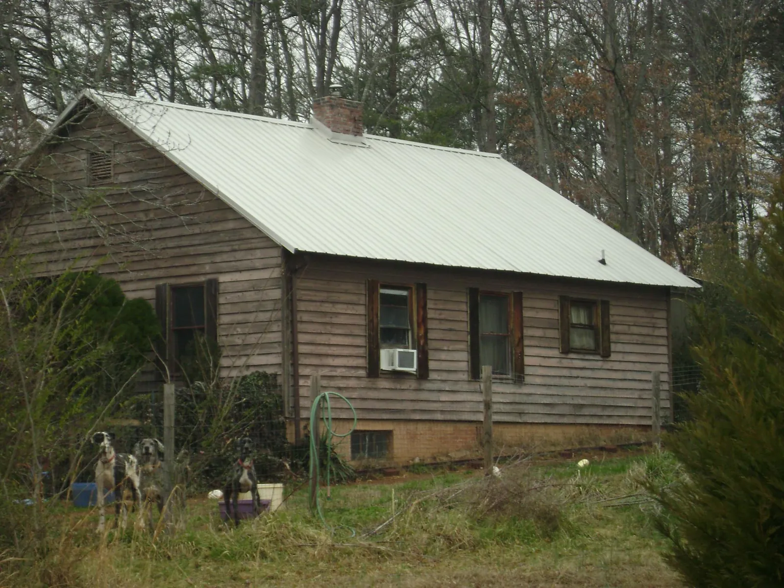 White metal roof on an old wood sided farmhouse, from a Metal Roof Installation job in Oak City