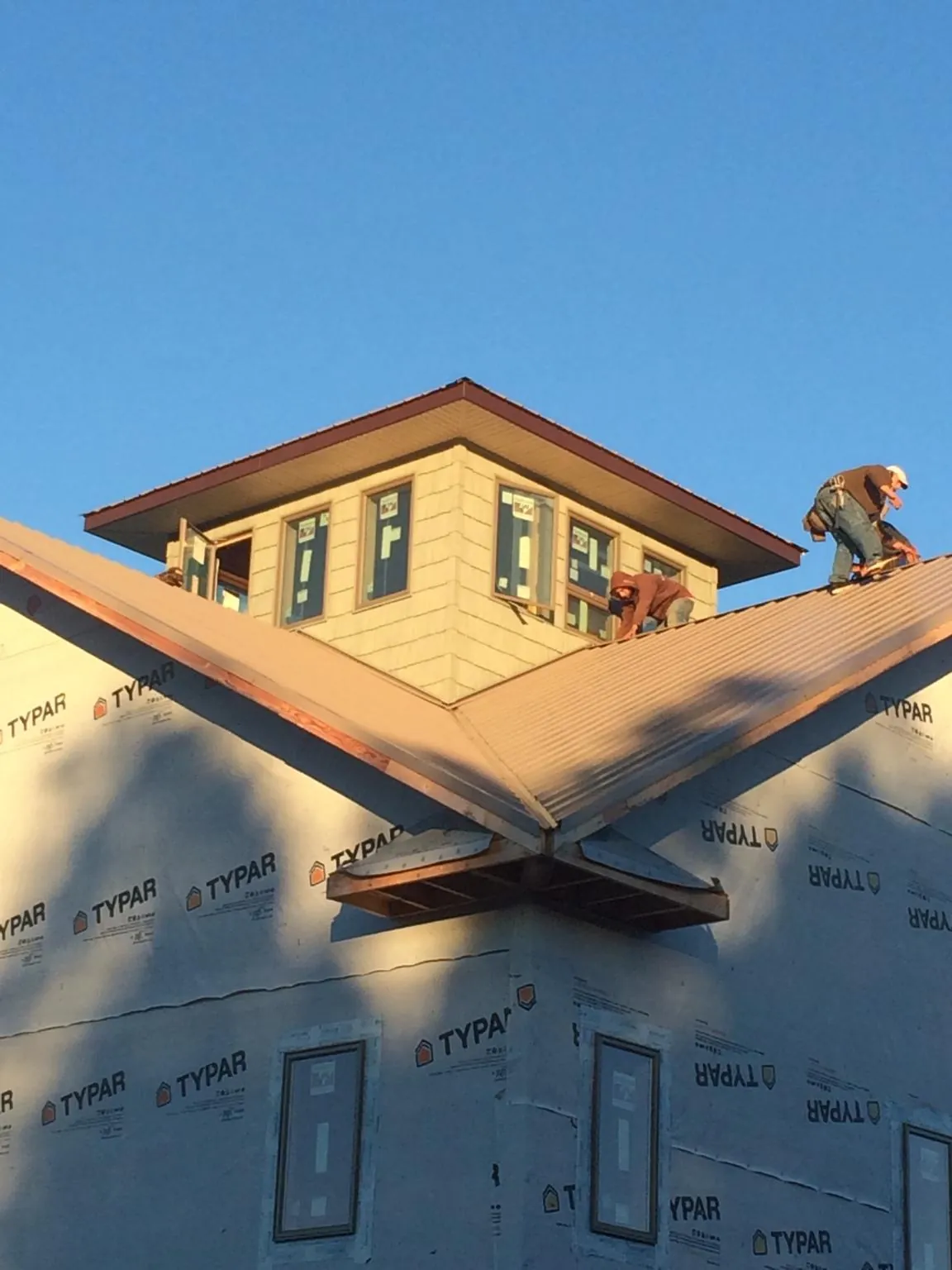 Roofers working around a rooftop cupola on a new metal roof at sunset — Roof Waterproofing in Oak City by Roofing Brothers